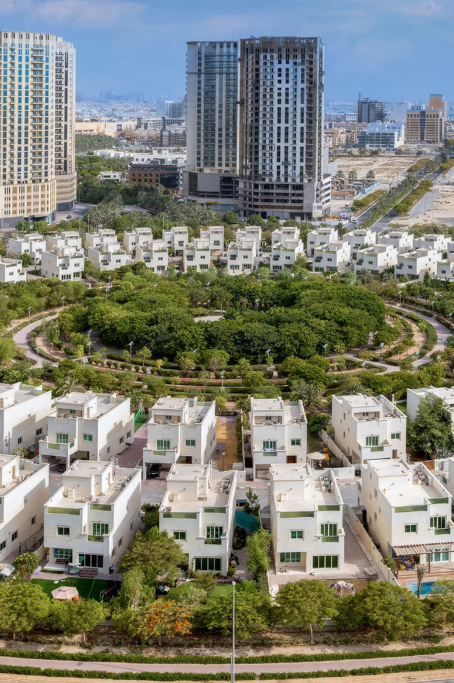 Aerial view of Jumeirah Village Circle: villas around the community park with residential towers beyond